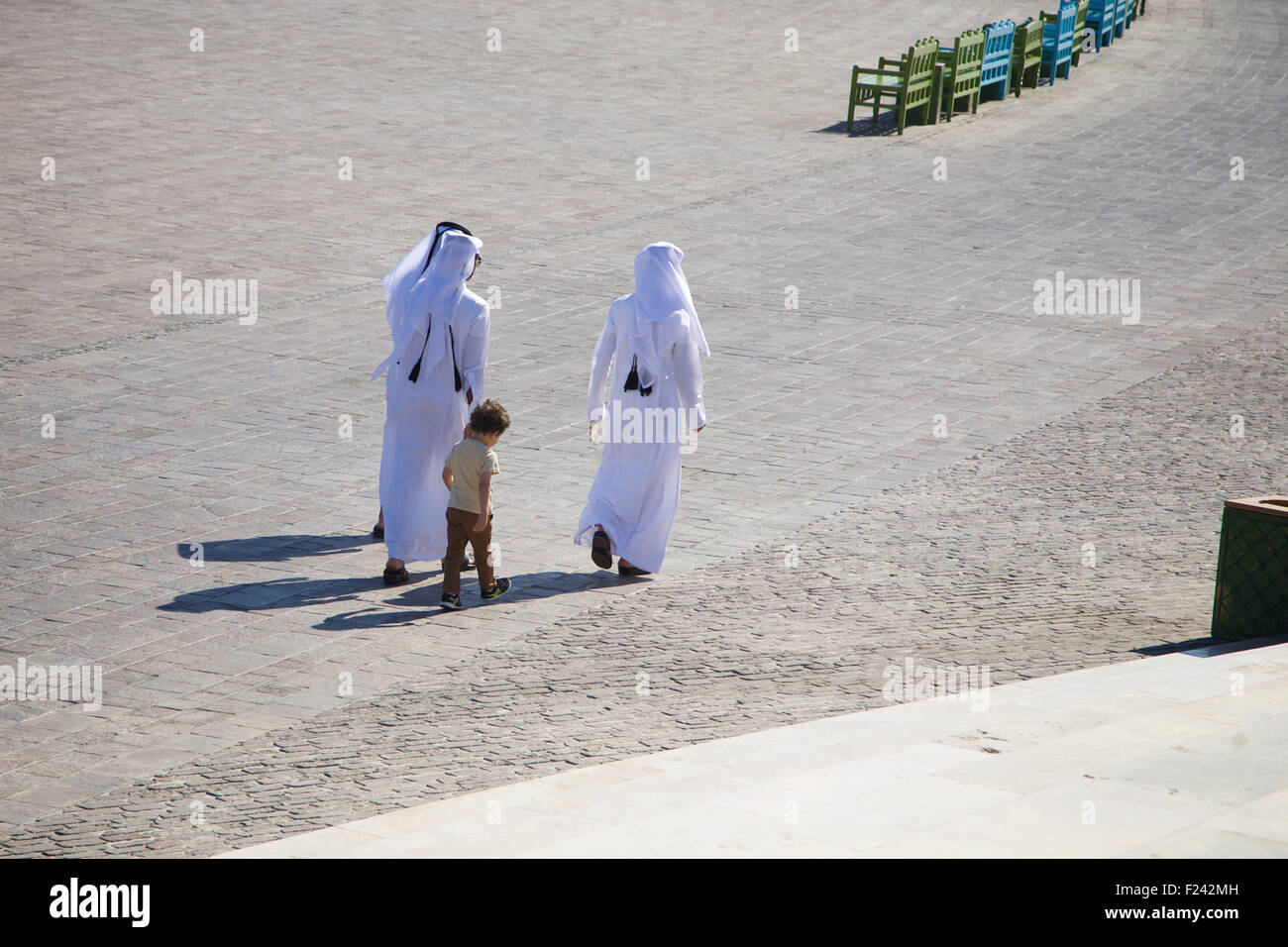 Three Qatari men take a stroll in the Qatara Amphitheatre with a young