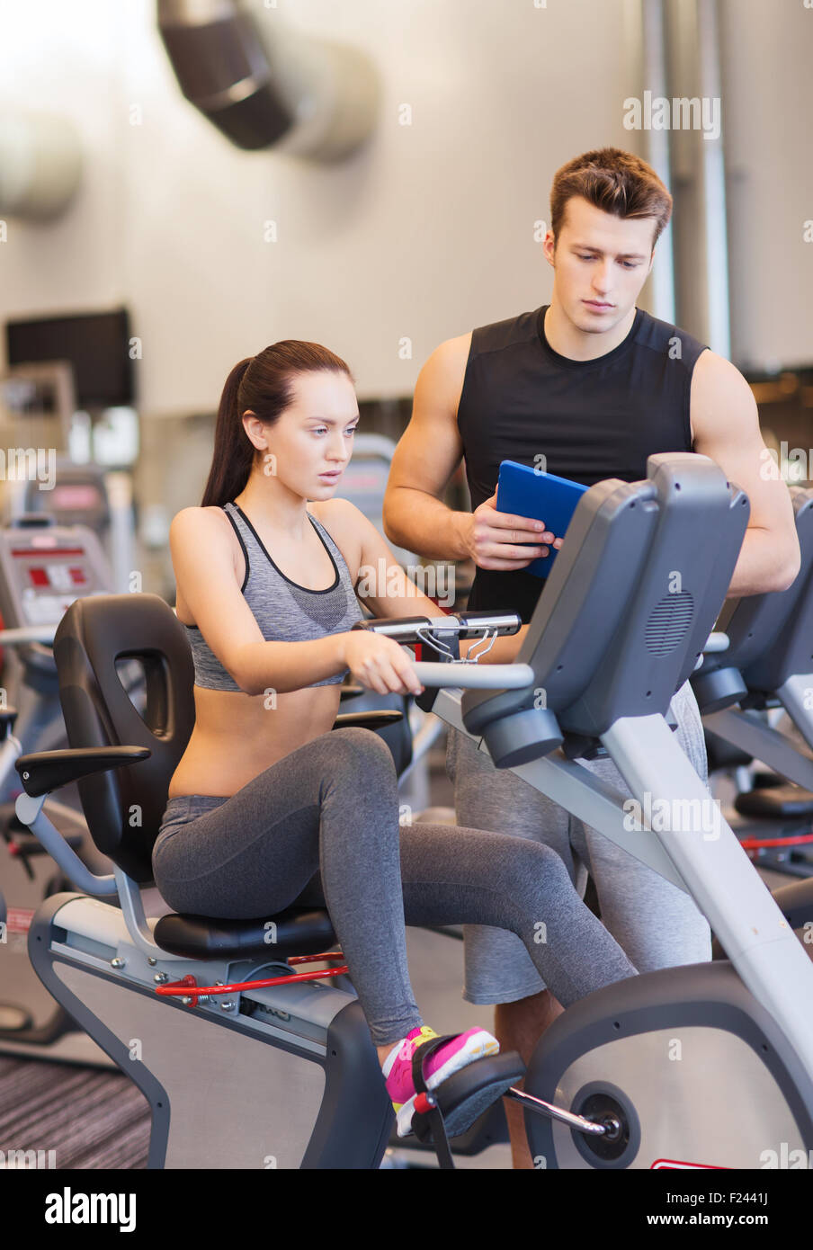 woman with trainer on exercise bike in gym Stock Photo - Alamy