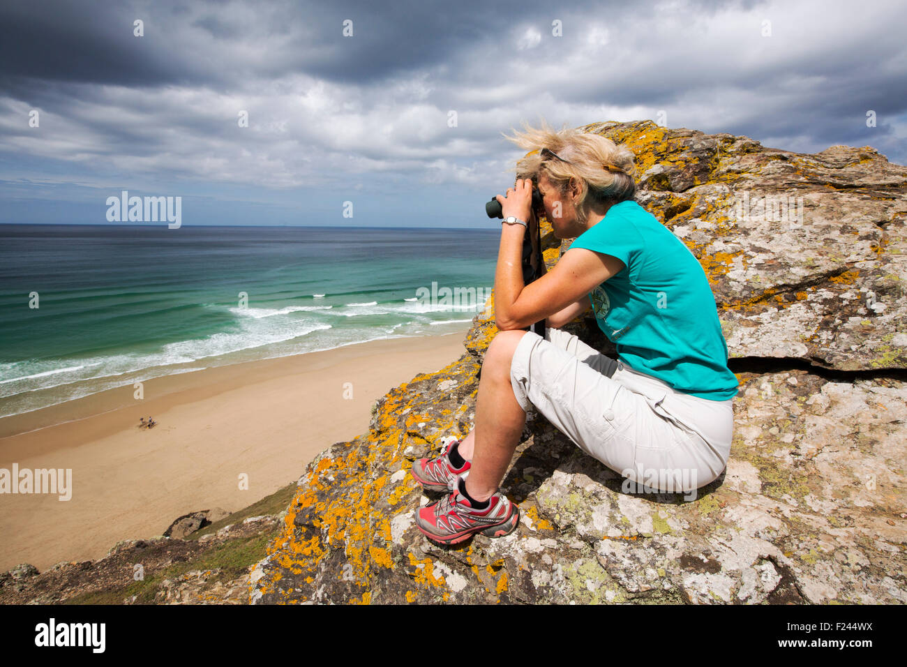 A woman sea watching on the cliffs at St Agnes, Cornwall, UK. Stock Photo