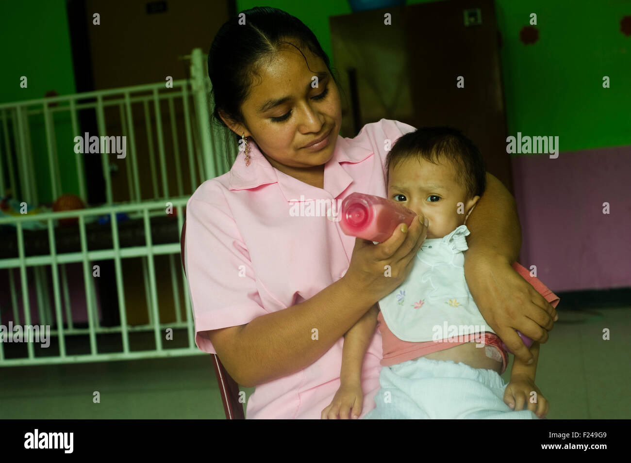 Guatemala, San Cristobal, nurse preparing F100 formula of complementary food for baby (Floricelda Isabel Lem 29, Andrea Dolores Coc 1 year 7 months) Stock Photo