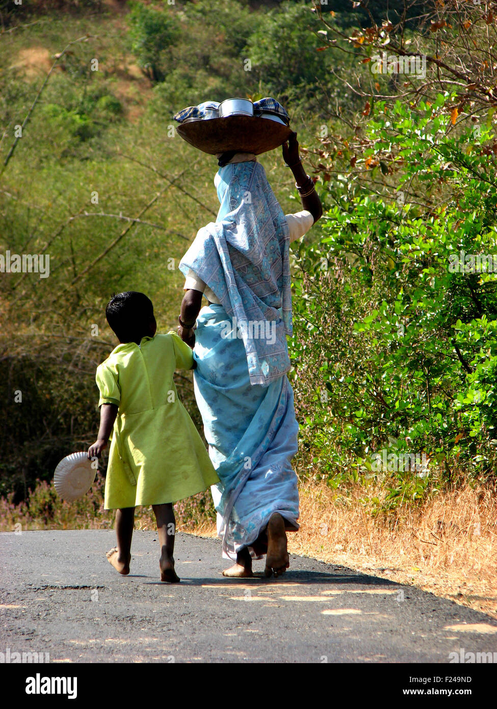 A little girl and a woman walk barren feet to reach water source in India during drought Stock Photo