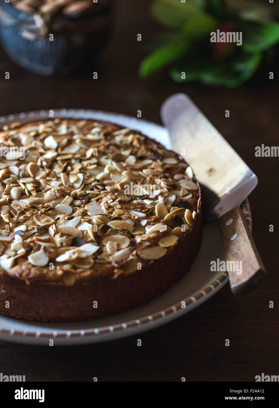 A Ricotta and Almond Polenta Cake displayed on a dark wood table. Stock Photo