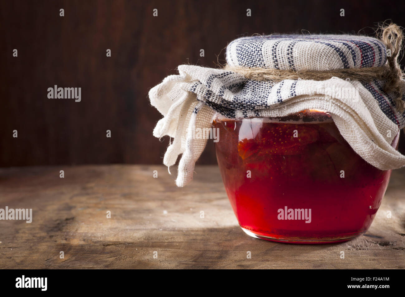 Homemade strawberry jam in glass jar with fresh berries on background on old rustic table Stock Photo