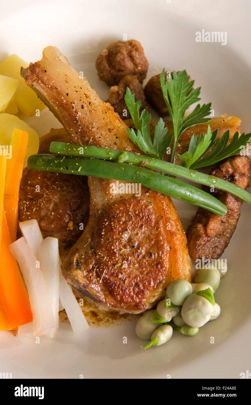 Lamb chops being cooked in a frying pan and served with vegetables. a