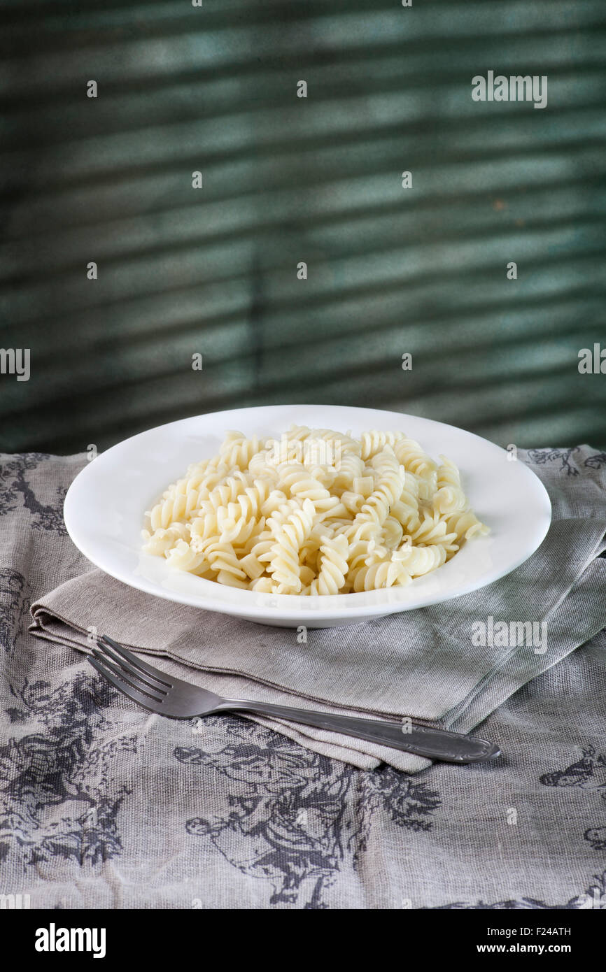 Pasta in the white plate on the table with sunlight shades on the blue background Stock Photo