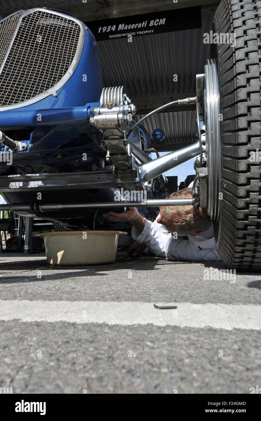 Goodwood Revival 2015. Mechanic works on a Maserati 8cm vintage racing car from underneath Stock Photo