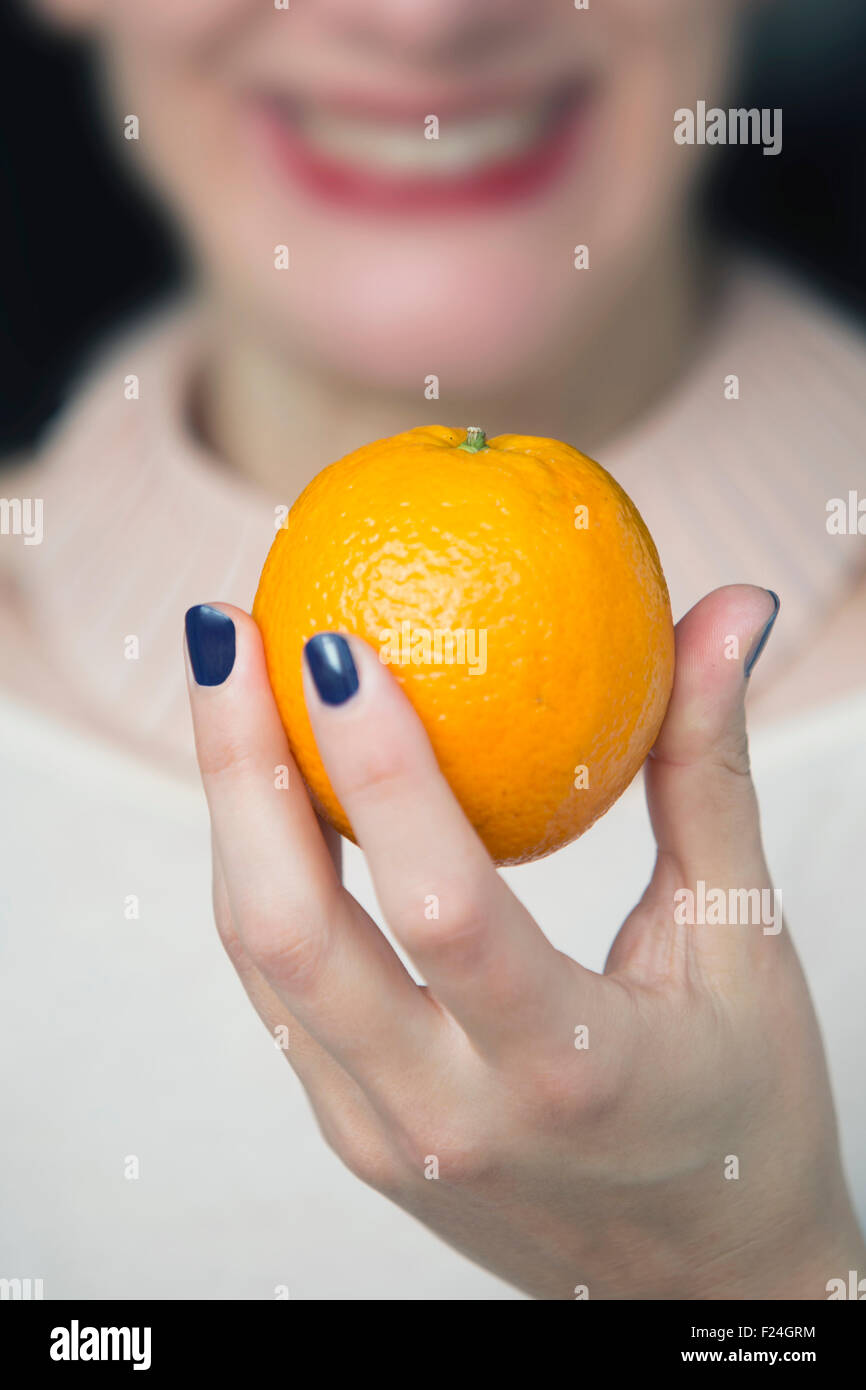 woman holding an orange in her hand and smiles Stock Photo - Alamy