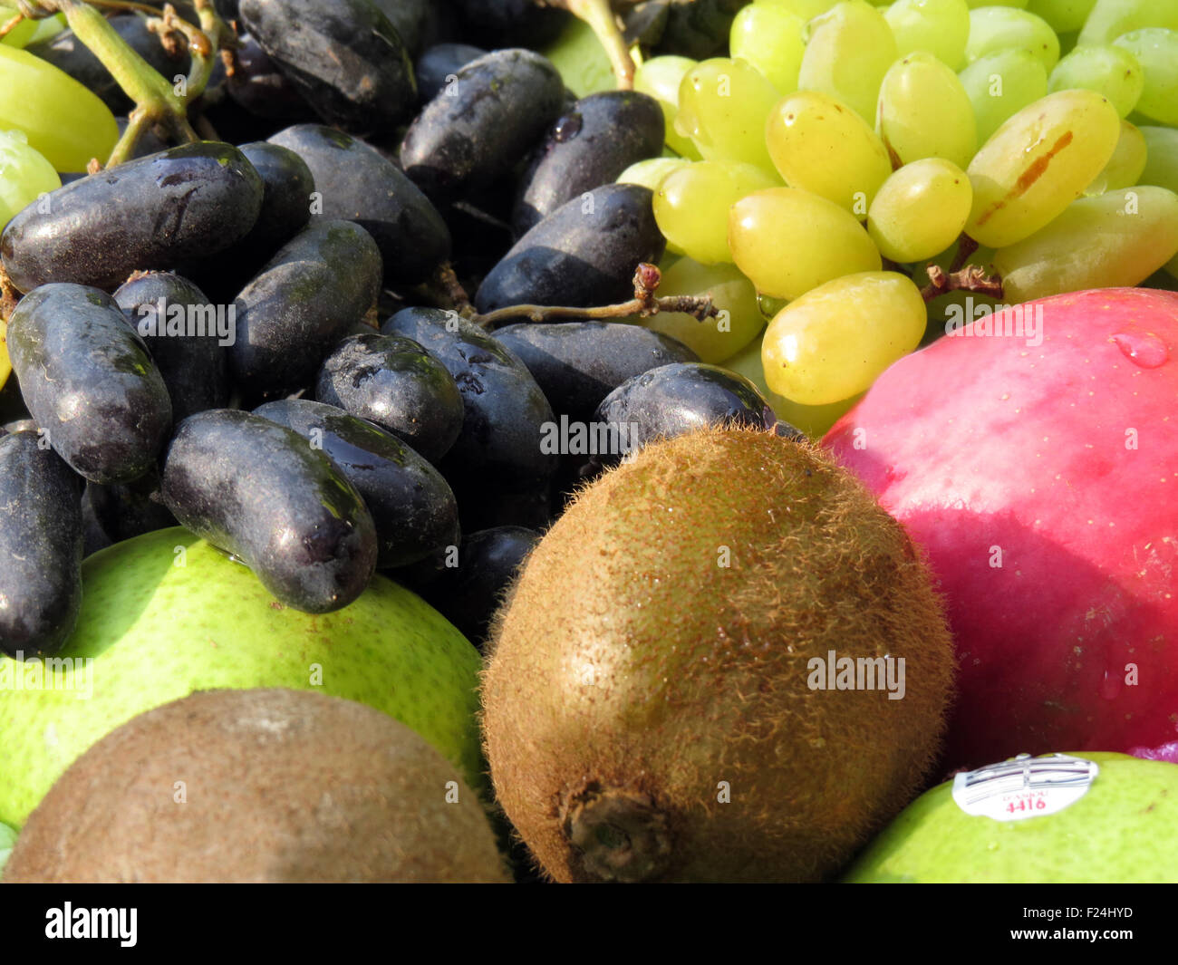 A background of different fresh fruits like yellow grapes, kiwi, apple and black grapes Stock