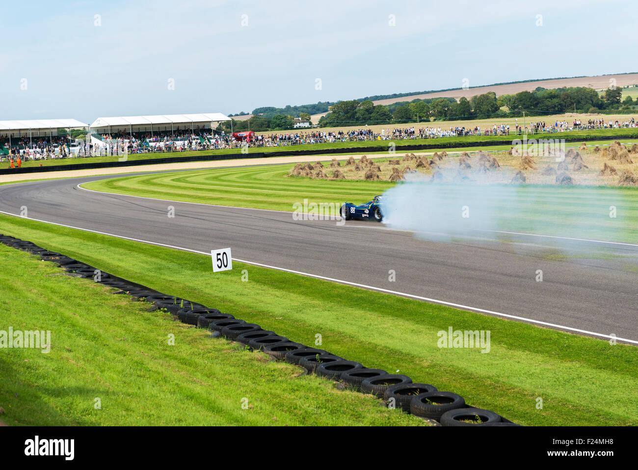 Goodwood, Chichester, West Sussex, UK. 11th September, 2015.  Image showing,Motorsport action thrills and spills during fridays practice session, with race losing traction and spinning out control showing crowds in background and smoke pouring from car tires. Stock Photo