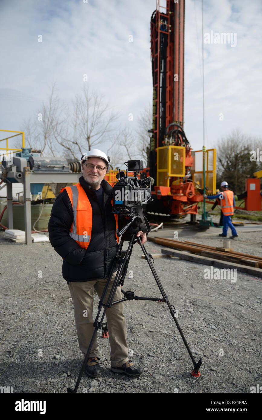 A documentary filmmaker poses with his camera on location Stock Photo
