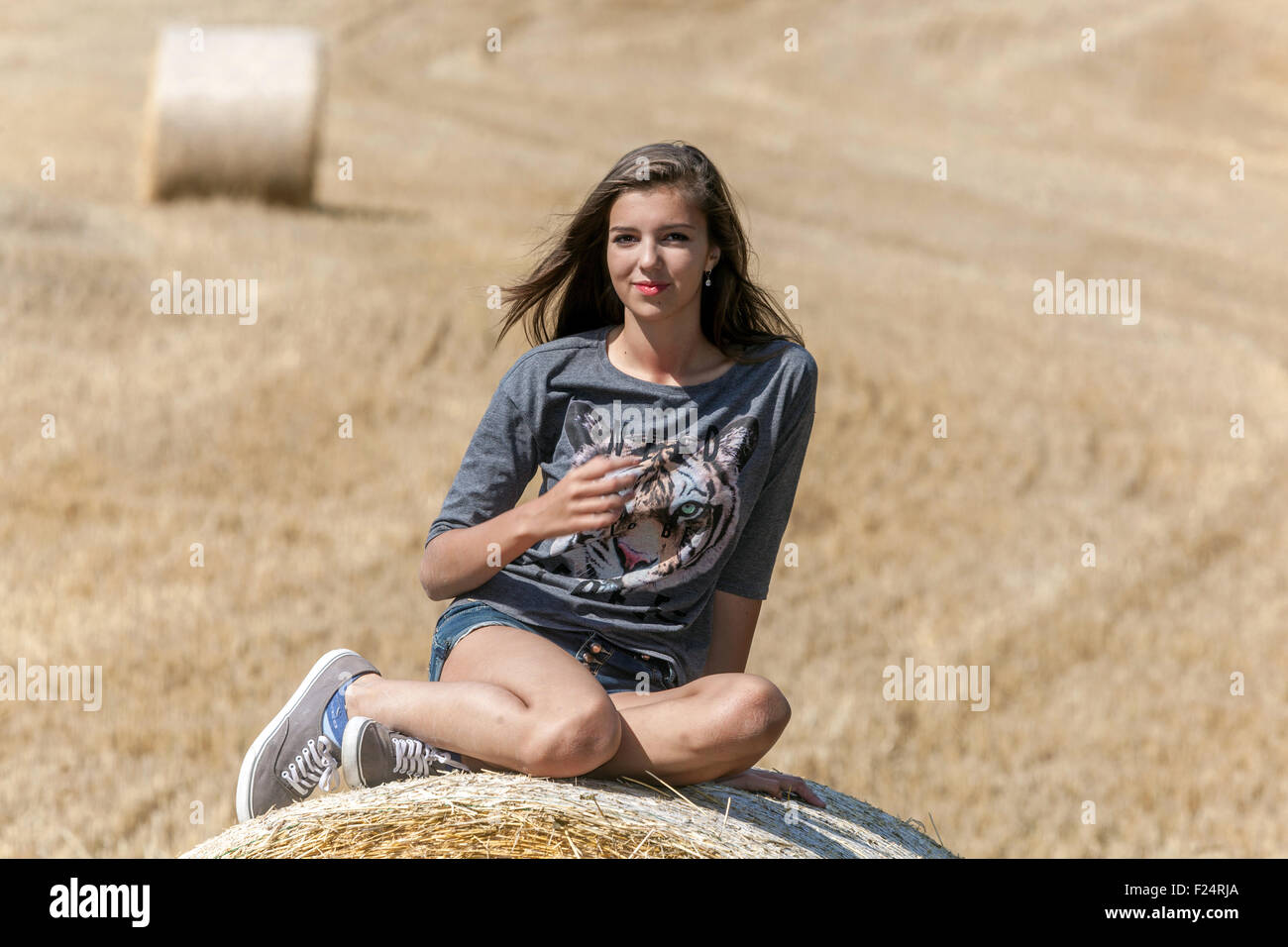 Young beautiful girl on straw bale Stock Photo