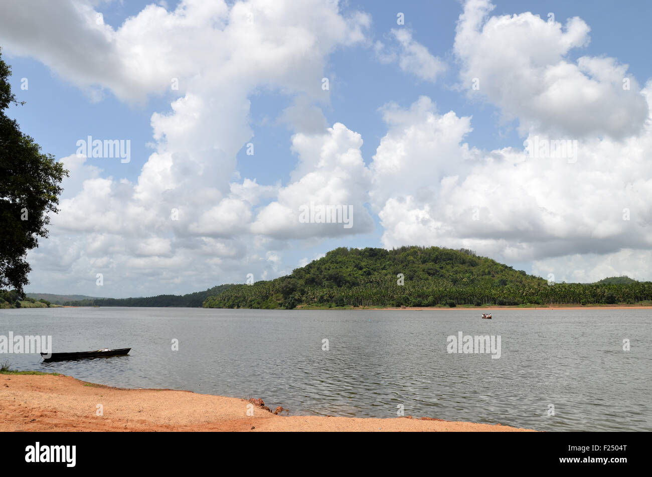 River front with beautiful clouds on a clear sky and green hill in the background Stock Photo