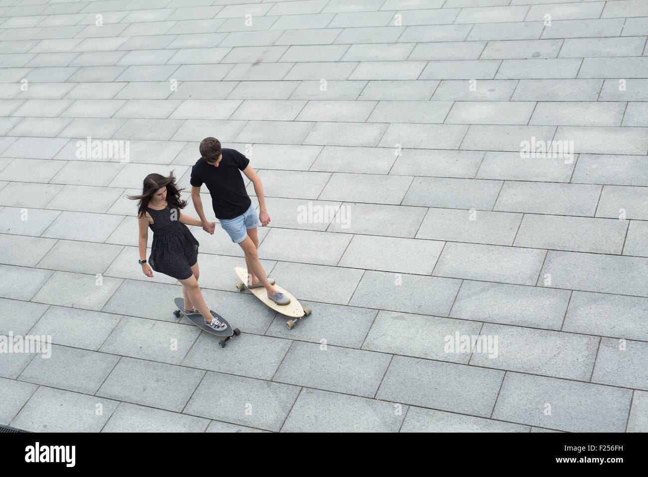 Young pair of stylish teenagers ride longboards Stock Photo