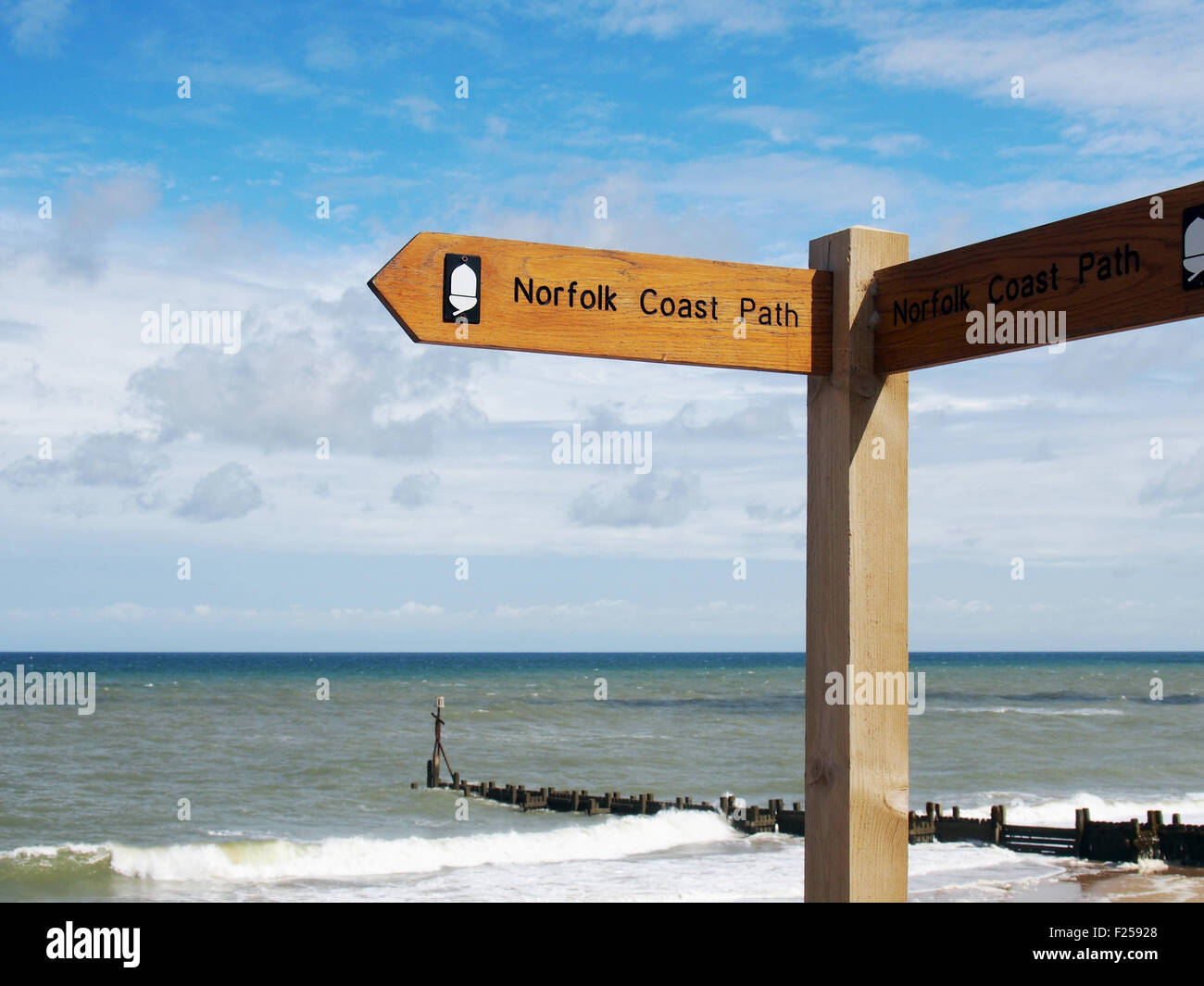 Norfolk Coastal Path footpath finger sign with the North Sea and Walcott beach in the background. Stock Photo