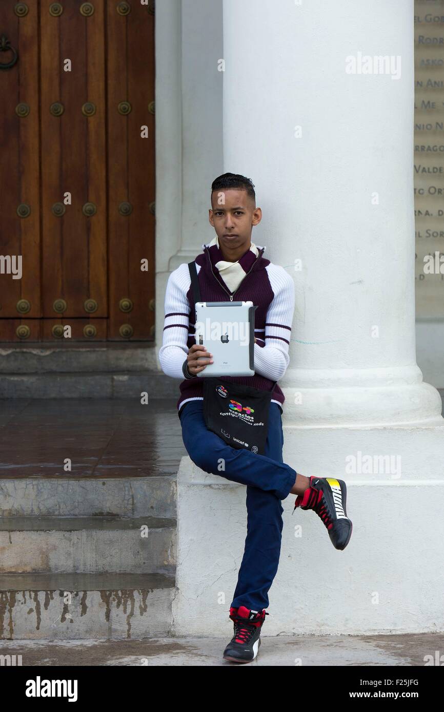 Cuba, Ciudad de la Habana province, Havana, Habana Vieja district listed as World Heritage by UNESCO, teenager with a digital tablet standing on Plaza Vieja square Stock Photo