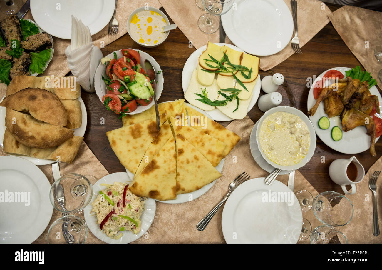 Table with Georgian food - traditional Georgian cheese filled bread called Imeretian khachapuri Stock Photo