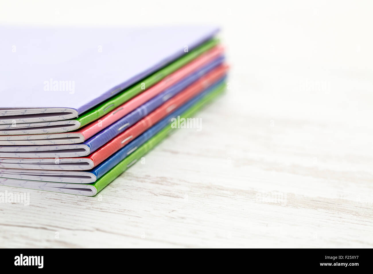 Image of a stack of colorful notebooks on a white wooden table Stock ...