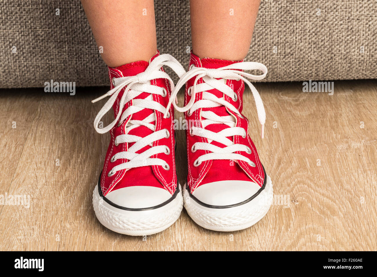Little girl wearing a pair of red sneakers at home Stock Photo - Alamy