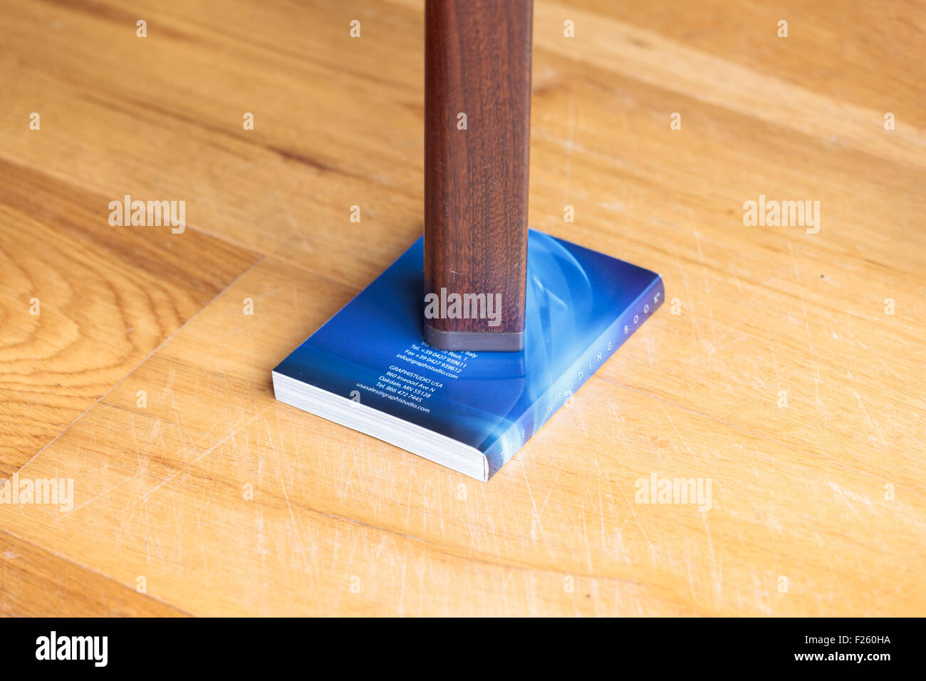 Leg of a wobbly table supported by a book Stock Photo - Alamy