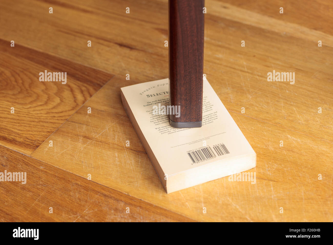 Leg of a wobbly table supported by a book Stock Photo