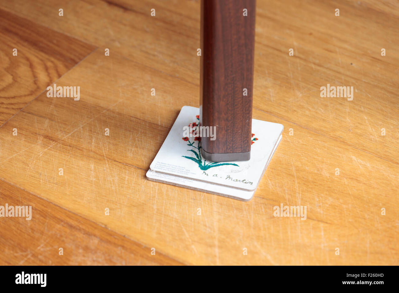 Leg of a wobbly table supported by coasters Stock Photo