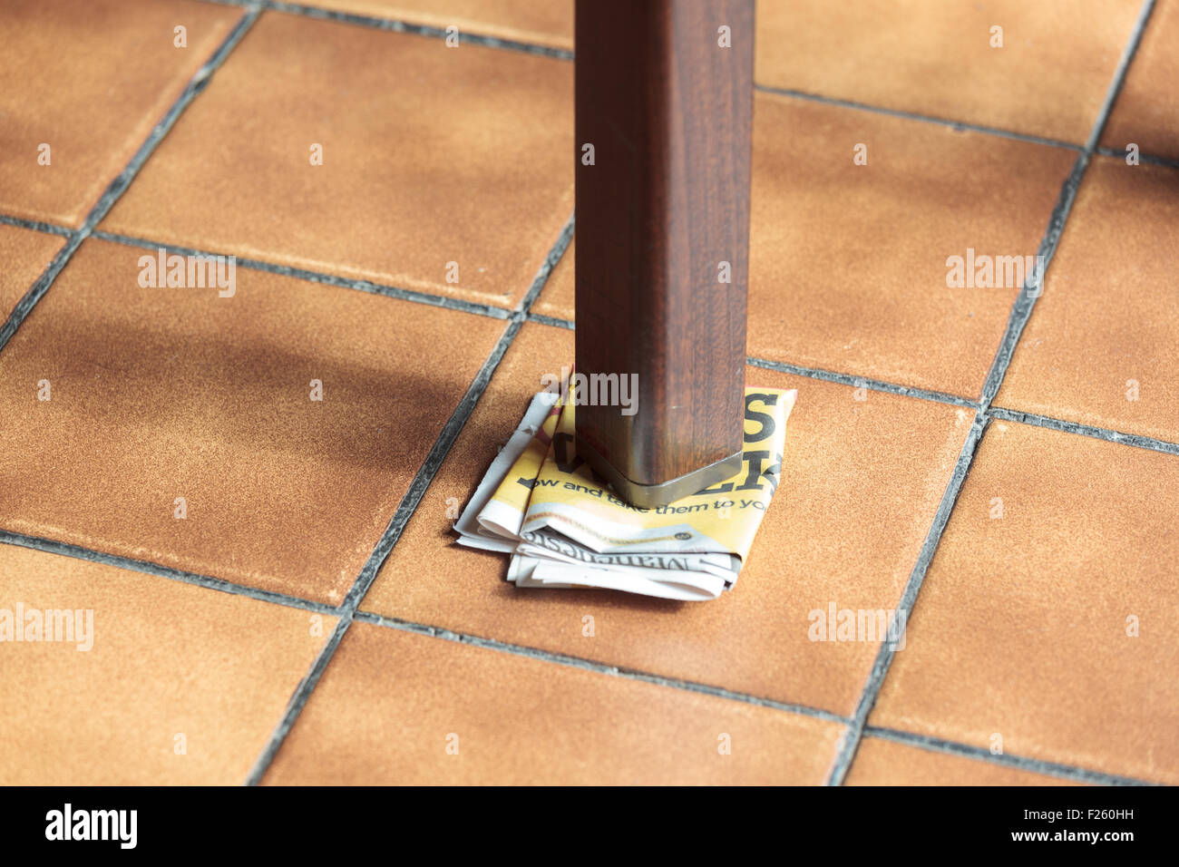 Leg of a wobbly table supported by folded paper Stock Photo