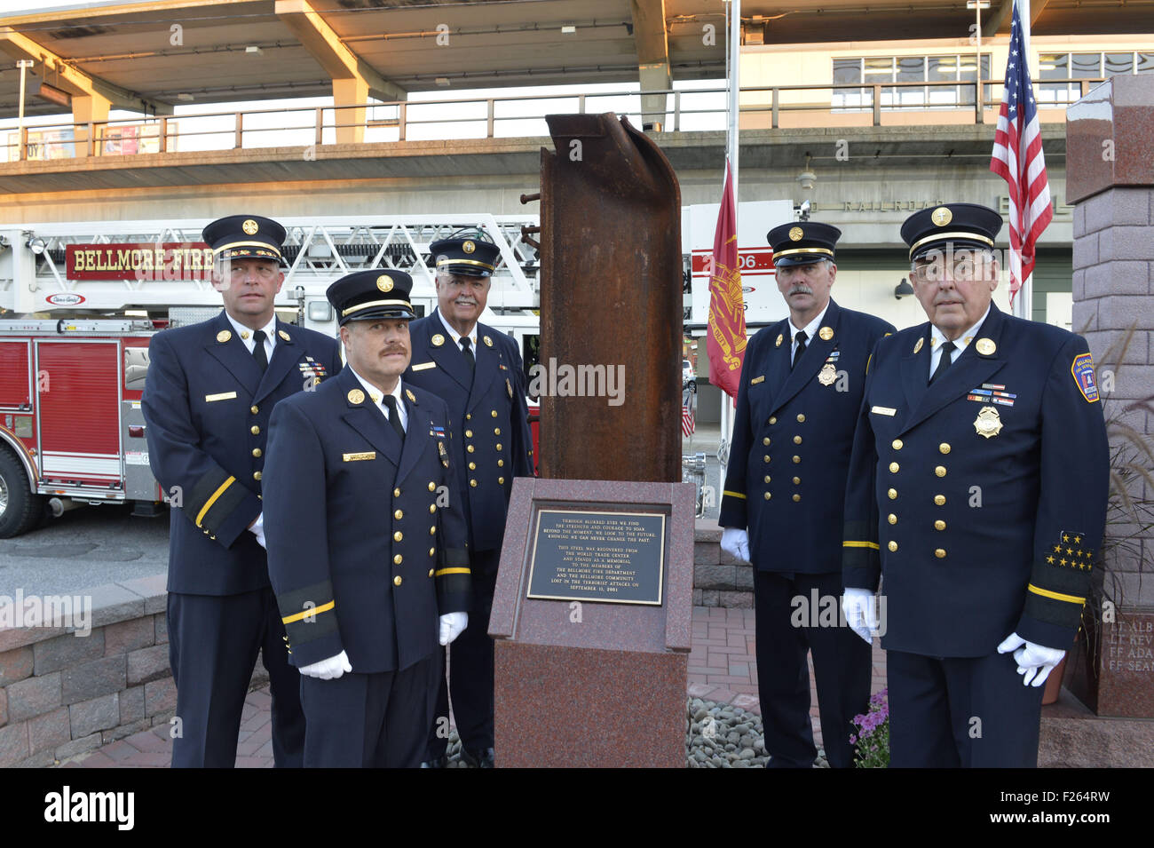 Bellmore, New York, USA. 11th Sep, 2015. L-R, Bellmore Fire Dept. Chief DANIEL HOLL, Pastor and Chaplain JAMES BARNUM, 1st Deputy VINCENT MONTERA, 2nd Deputy TOM STOERGEN, and Chaplain DENNIS RICH stand next to a monument that's a piece of structural steel from the Twin Towers, during the Bellmore Memorial Ceremony for 3 Bellmore volunteer firefighters and 7 residents who died due to 9/11 NYC terrorist attacks. Elevated platform of Bellmore LIRR Station is in background. © Ann Parry/ZUMA Wire/Alamy Live News Stock Photo