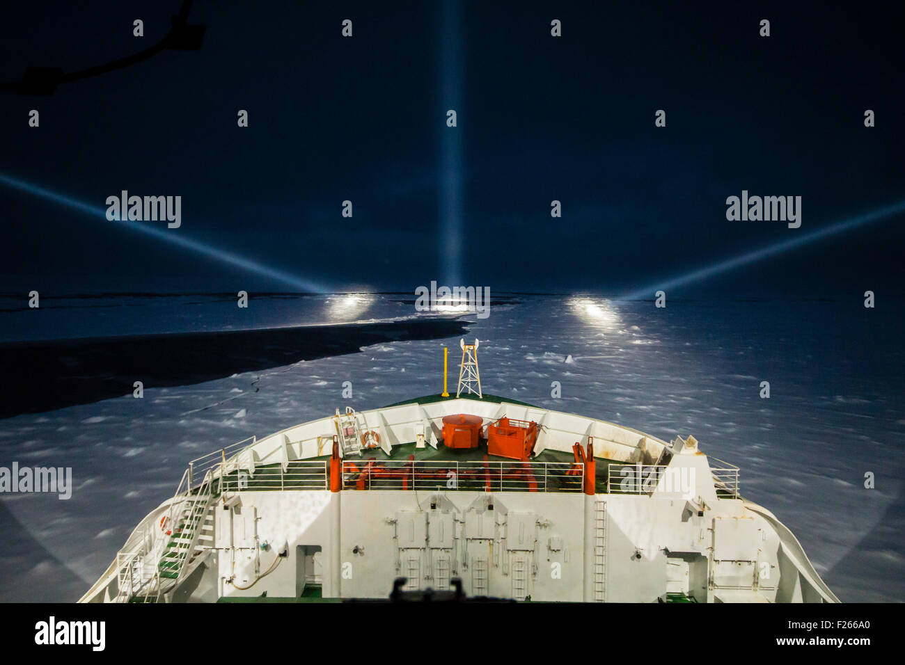 Icebreaker ship cruising at night by the aid of night-piercing projectors in the polar sea Stock Photo