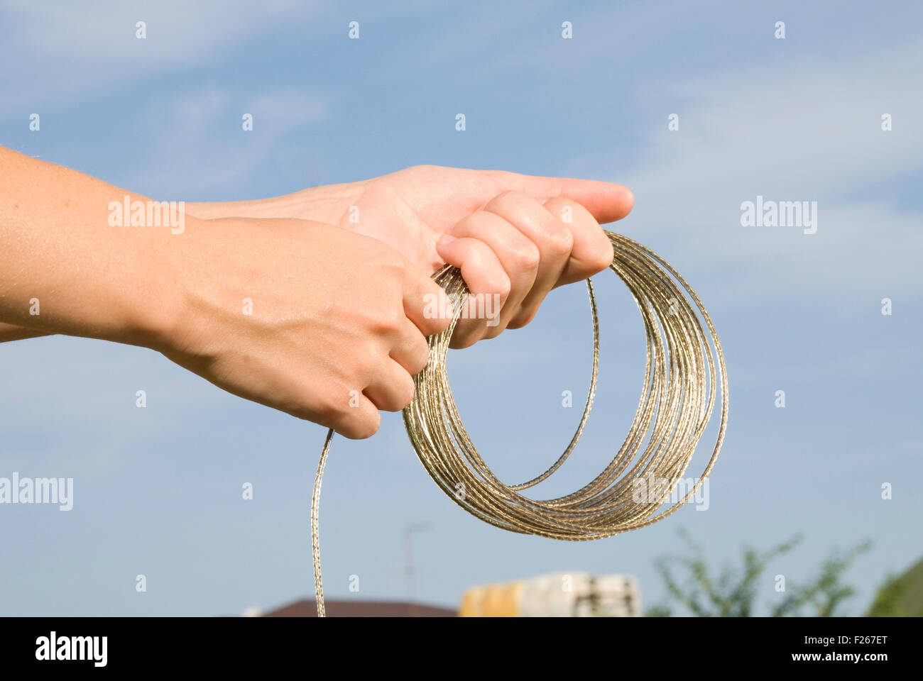 shiny rope in hands on sky background Stock Photo - Alamy