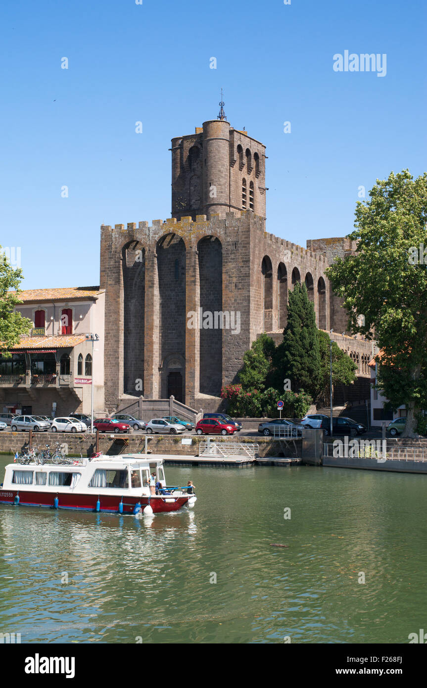 Boat on the river Hérault passing the cathedral at Agde,  Hérault,  Languedoc-Roussillon, France, Europe Stock Photo