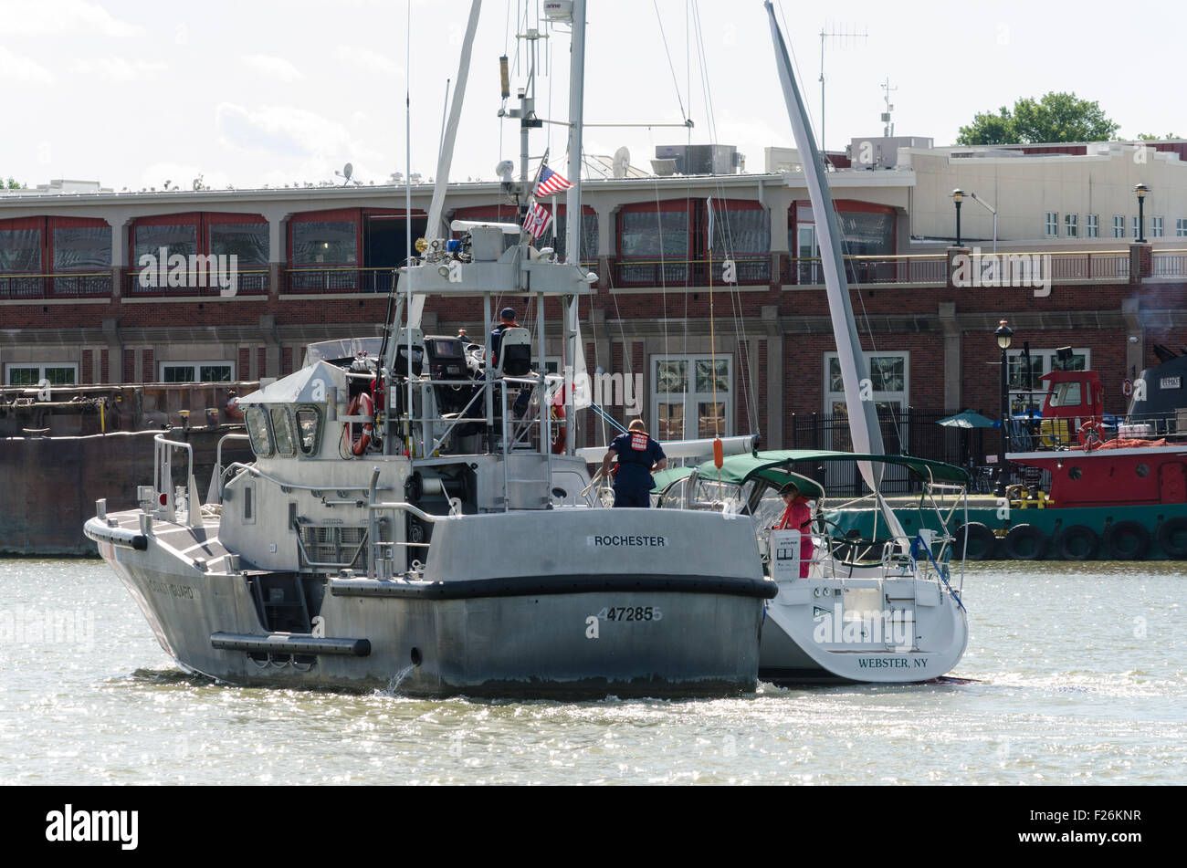 Coast guard boat with sail boat goes upstream in Port of Rochester NY. Stock Photo