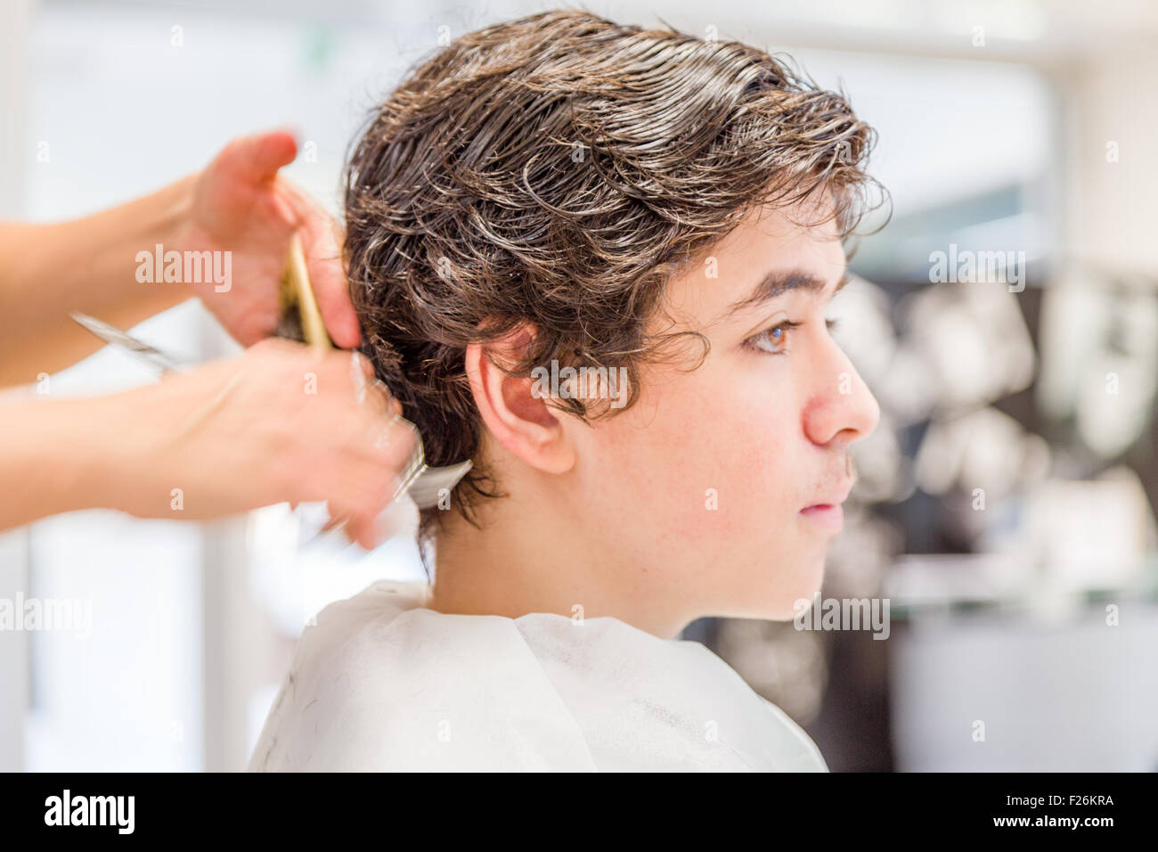 Cute Caucasian Teenage Boy Sitting At The Hairdresser Salon For A