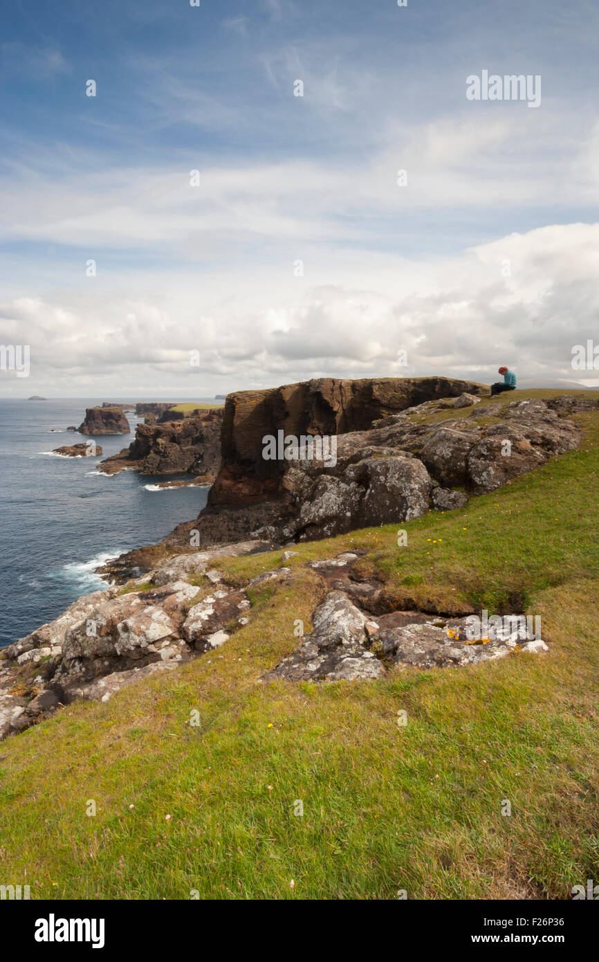 Girl sitting on rock, Eshaness, Northmavine, Shetland, Northern Isles, Scotland, UK Stock Photo