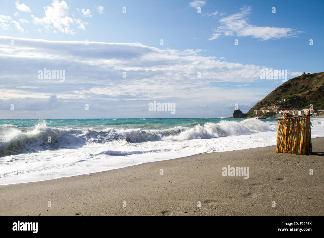 the waves breaking on the deserted beach, the background blue sky and clouds Stock Photo