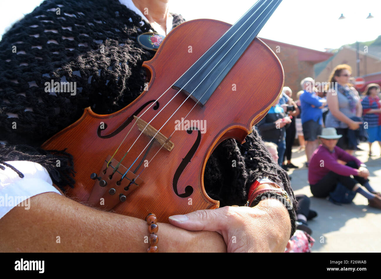 Woman holds her violin during folk festival at Whitby. Out of focus