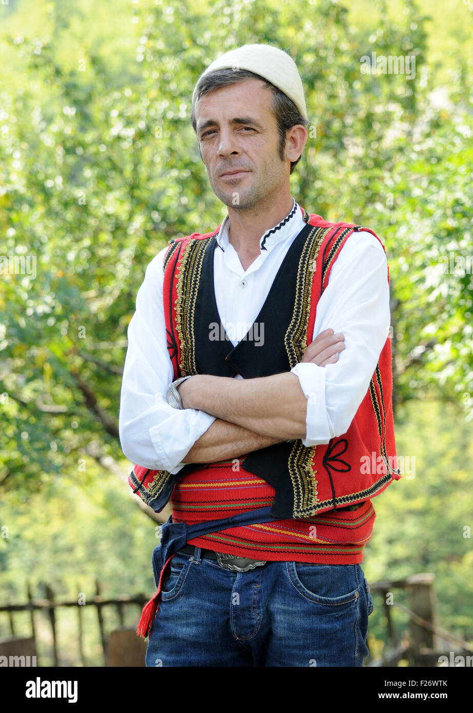 The guardian of Theth's stone lock-in tower in national dress. Theth, Thethi, Albania. Stock Photo