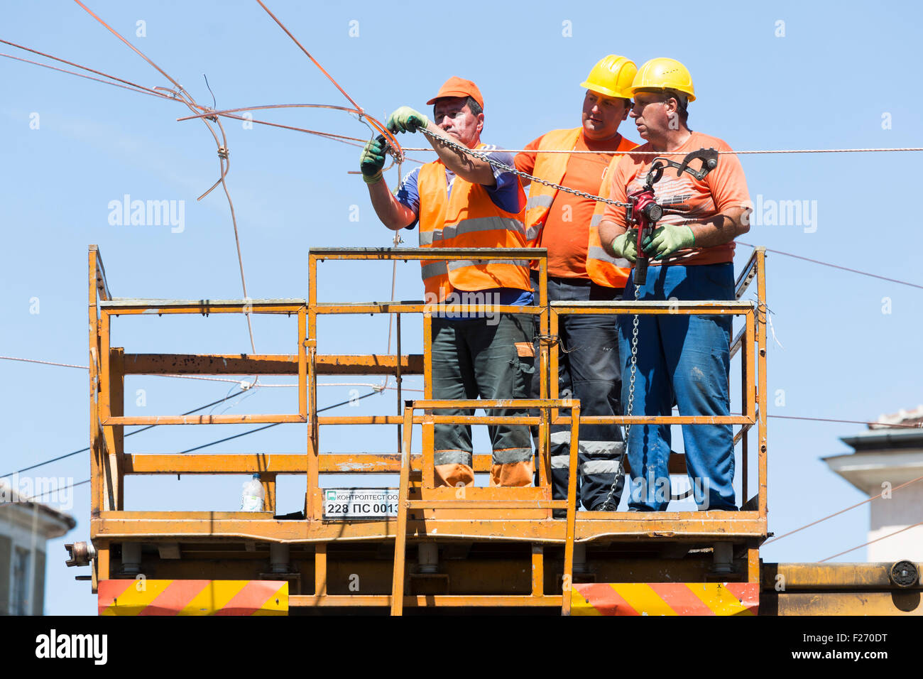 Sofia, Bulgaria - August 18, 2015: Three electricity construction workers on a platform are repairing tram's wires. Stock Photo