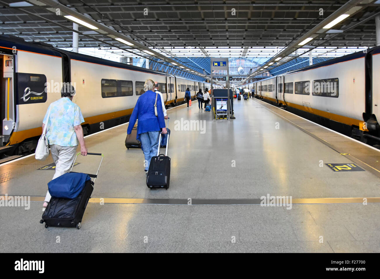 Eurostar train St Pancras International Eurostar station platform two elder women passengers lugging suitcases towards exits Camden London England UK Stock Photo