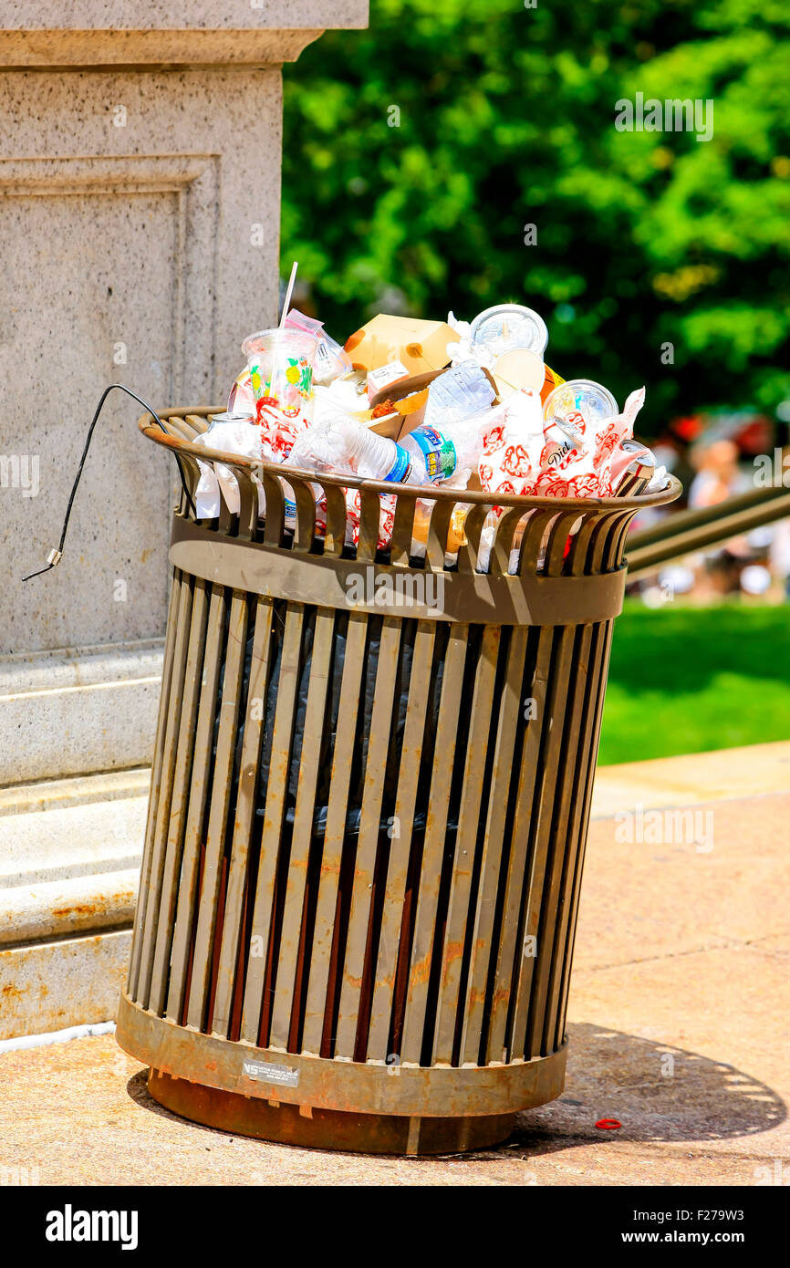 A trash can overflowing with empty drinks containers and food wrappers