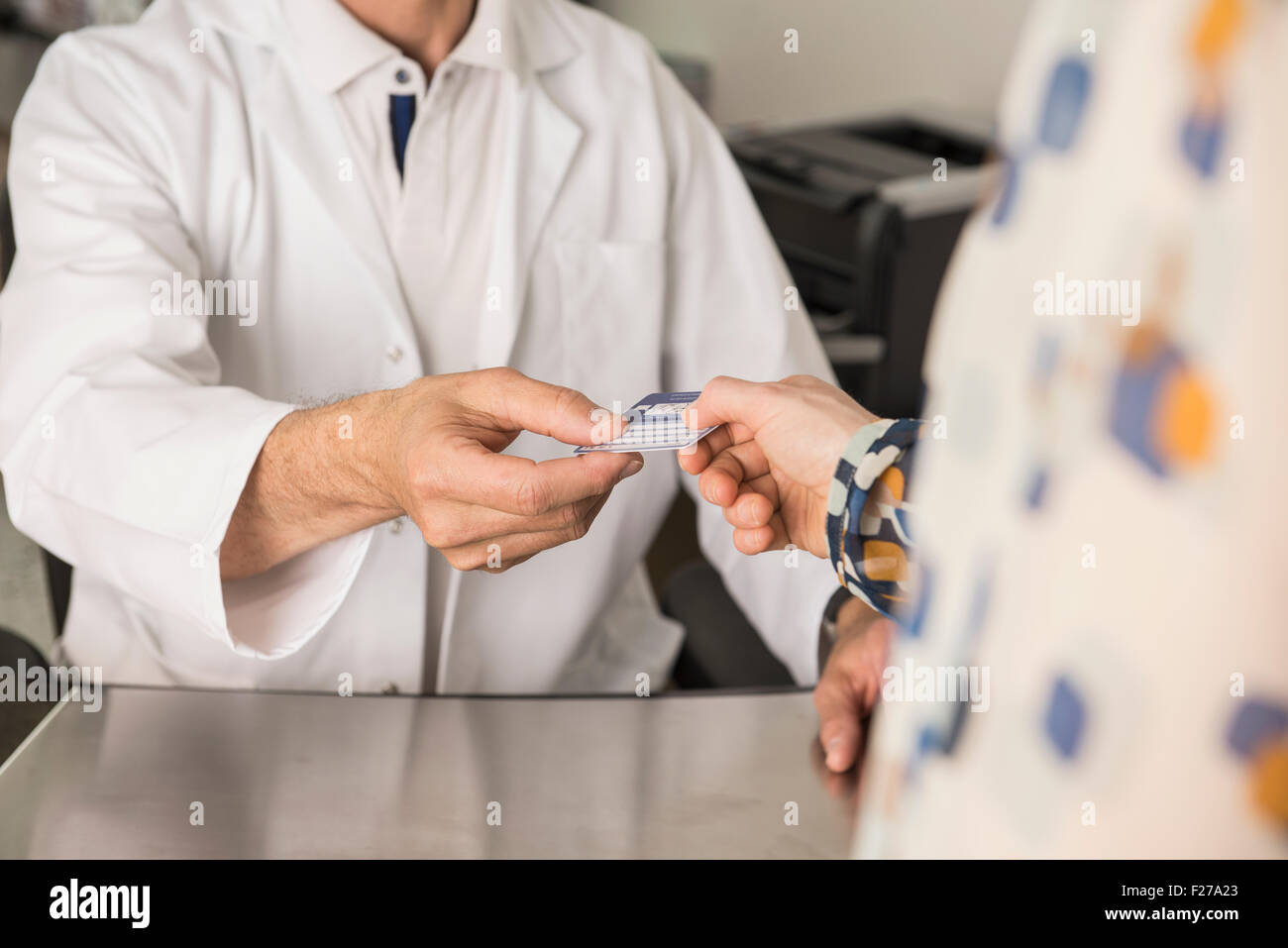 Patient giving a health insurance card to doctor, Munich, Bavaria, Germany Stock Photo