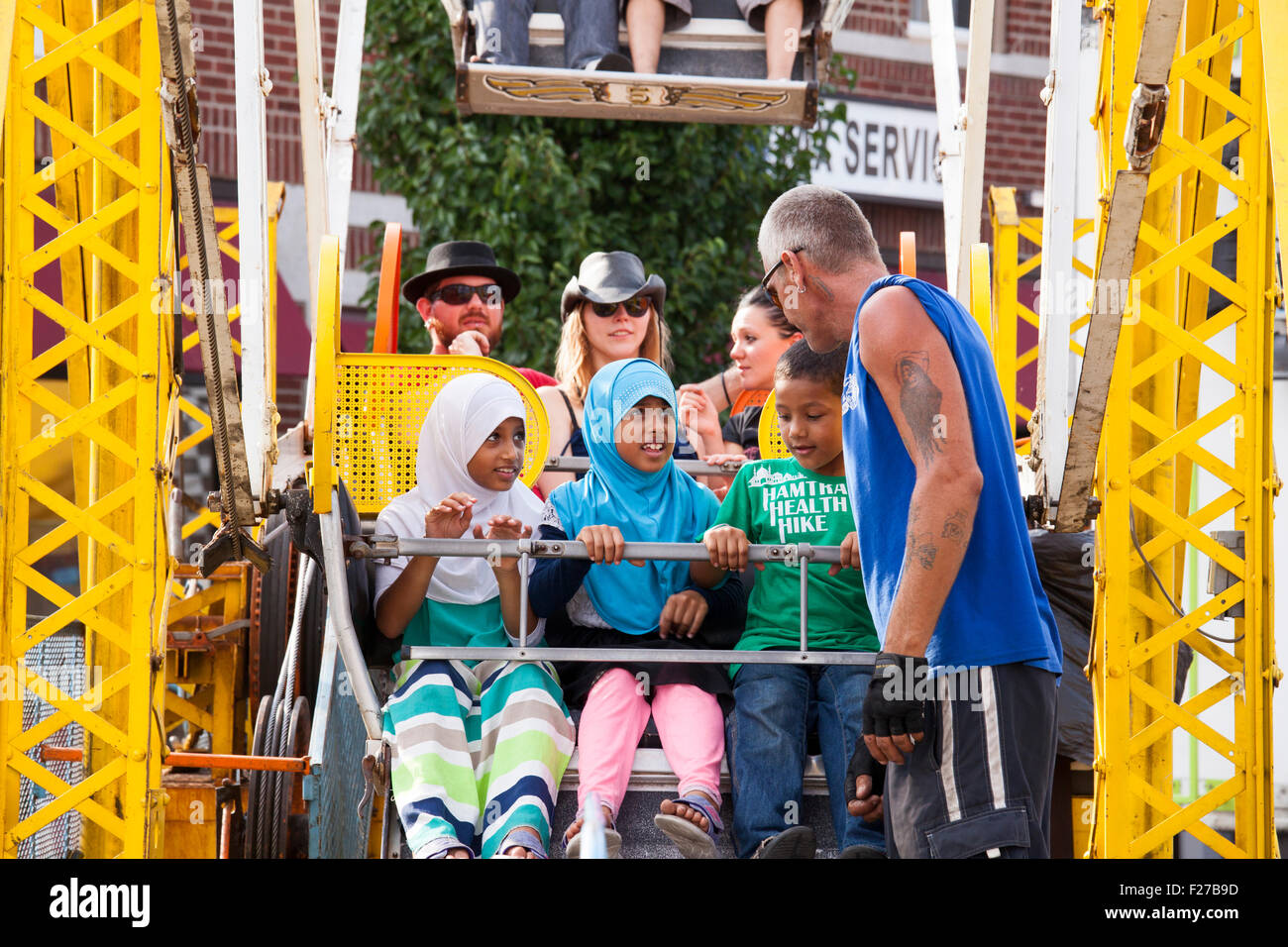 Hamtramck, Michigan - A worker fastens children into a ferris wheel during Hamtramck's Labor Day festival. Stock Photo