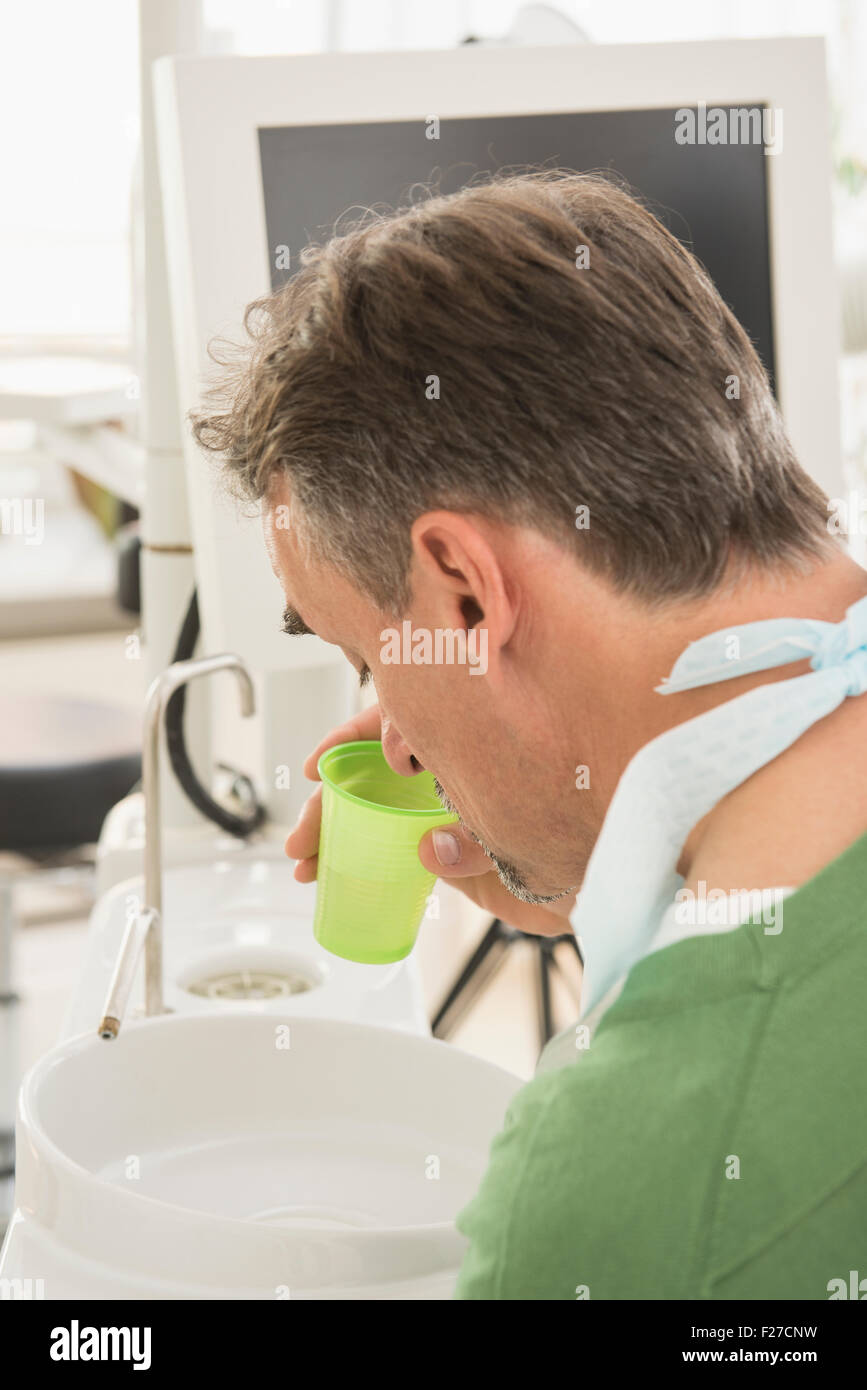 Dental patient spitting into a cuspidor in the dentists office, Munich