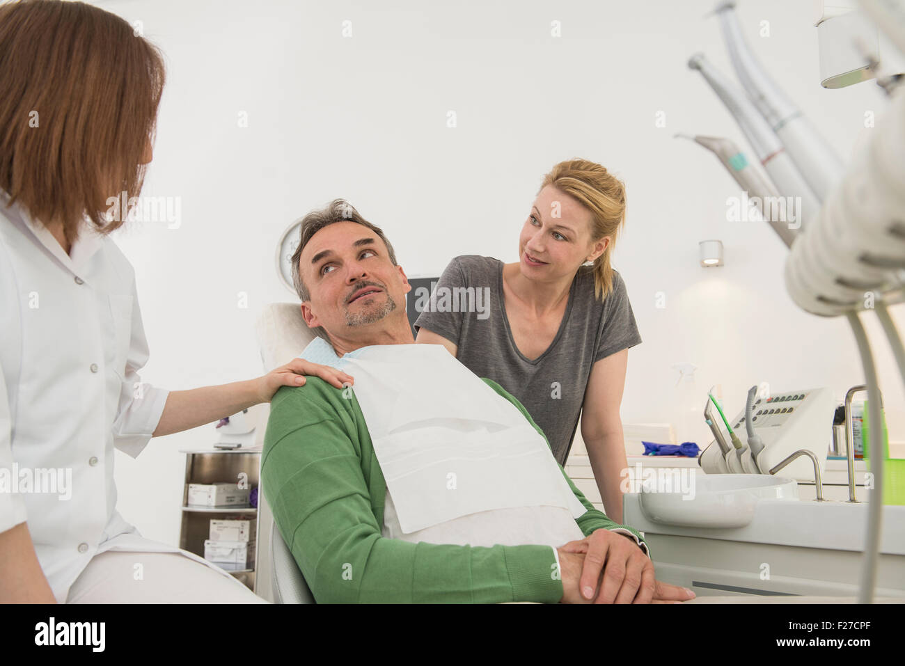 Female dentist and dental assistant talking to patient , Munich