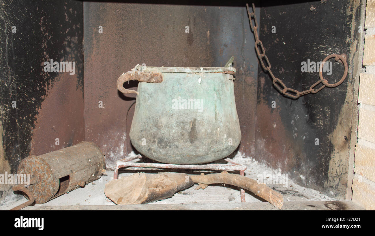 Old fireplace of a country house, inside an old copper pot with old farm tools over the fireplace. Stock Photo