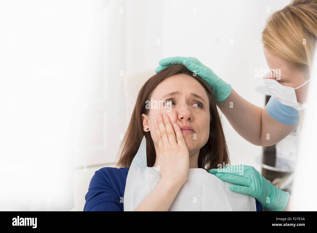 Female doctor consoling patient suffering from toothache, Munich, Bavaria, Germany Stock Photo