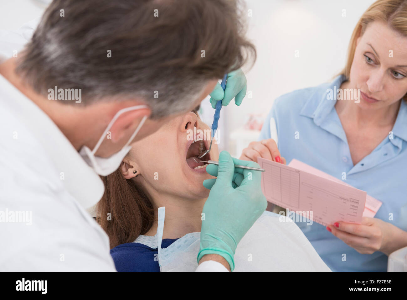 Dentist examining patient and dictating the findings to the assistant, Munich, Bavaria, Germany Stock Photo