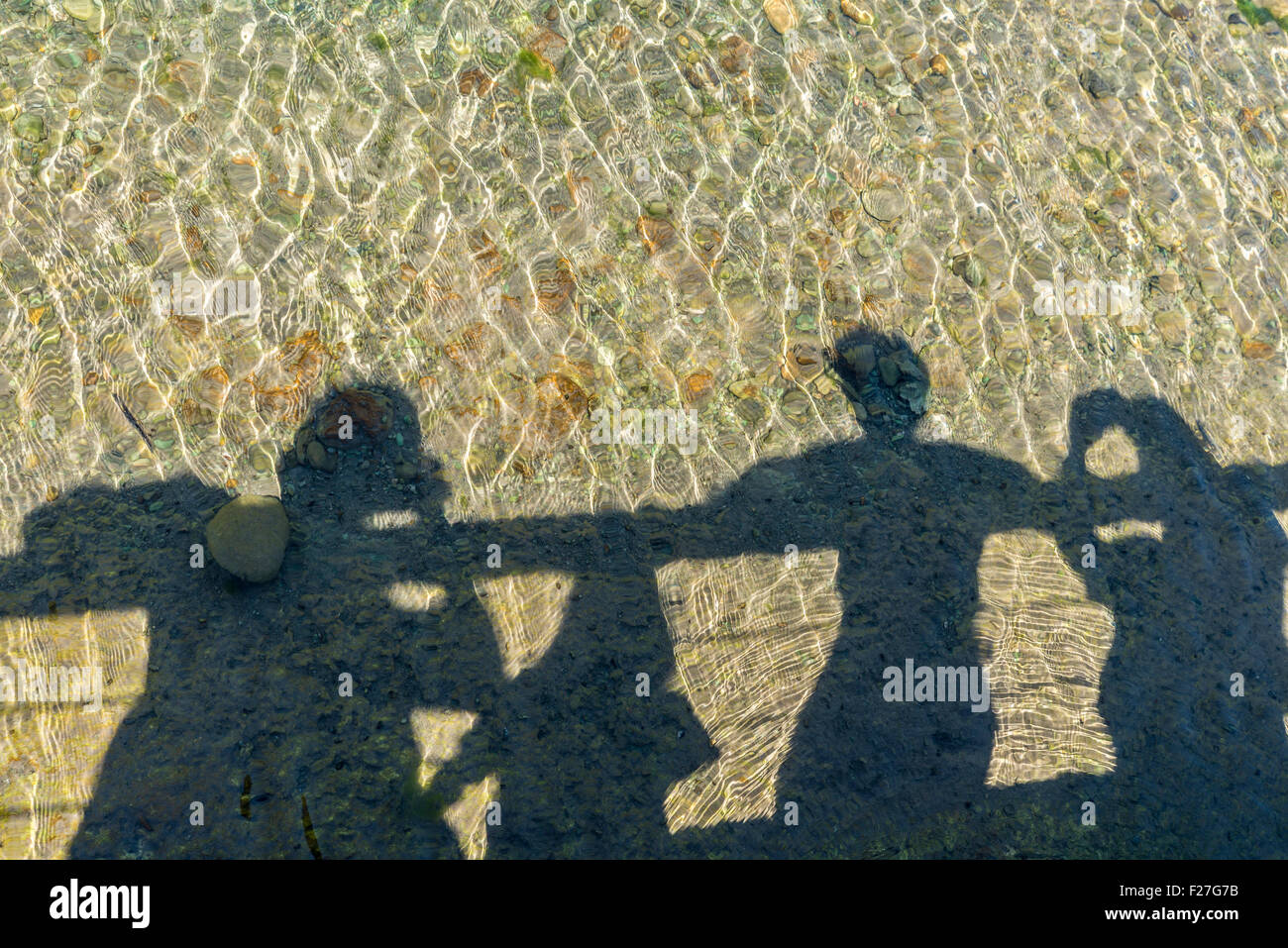 Shadows of the members of a family reflected in a river while watching from a bridge Stock Photo