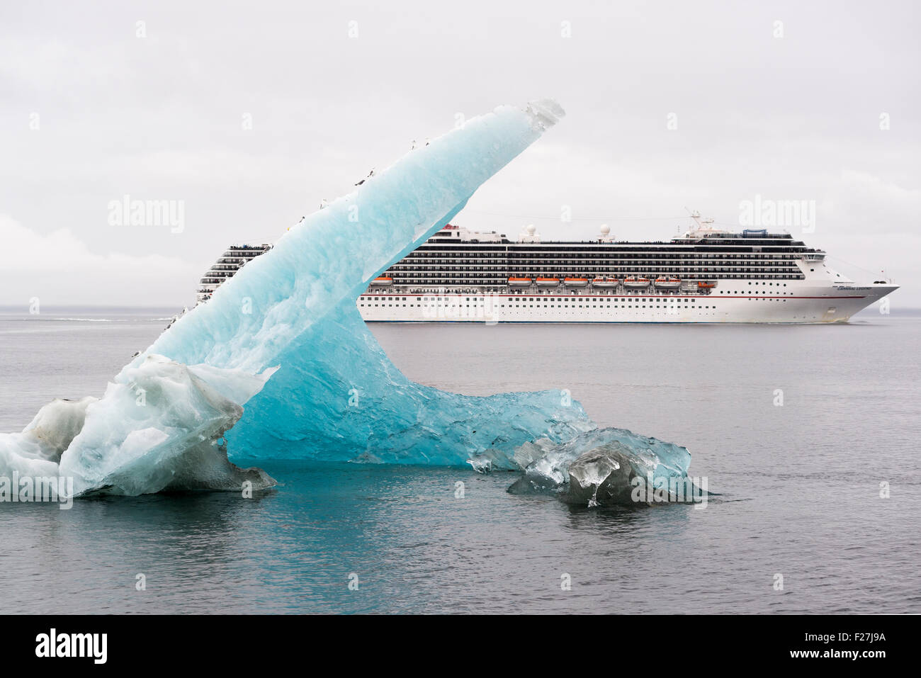 Carnival Legend cruise ship and an iceberg with gulls in Stephen's Passage, Alaska. Stock Photo