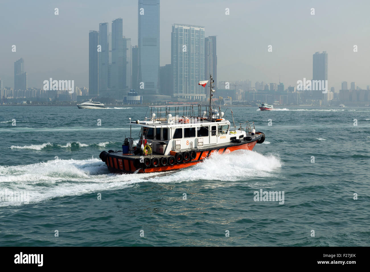 Harbour pilot boat moving at speed through Victoria harbour Hong Kong. Tall buildings of Kow Loon in the background Stock Photo