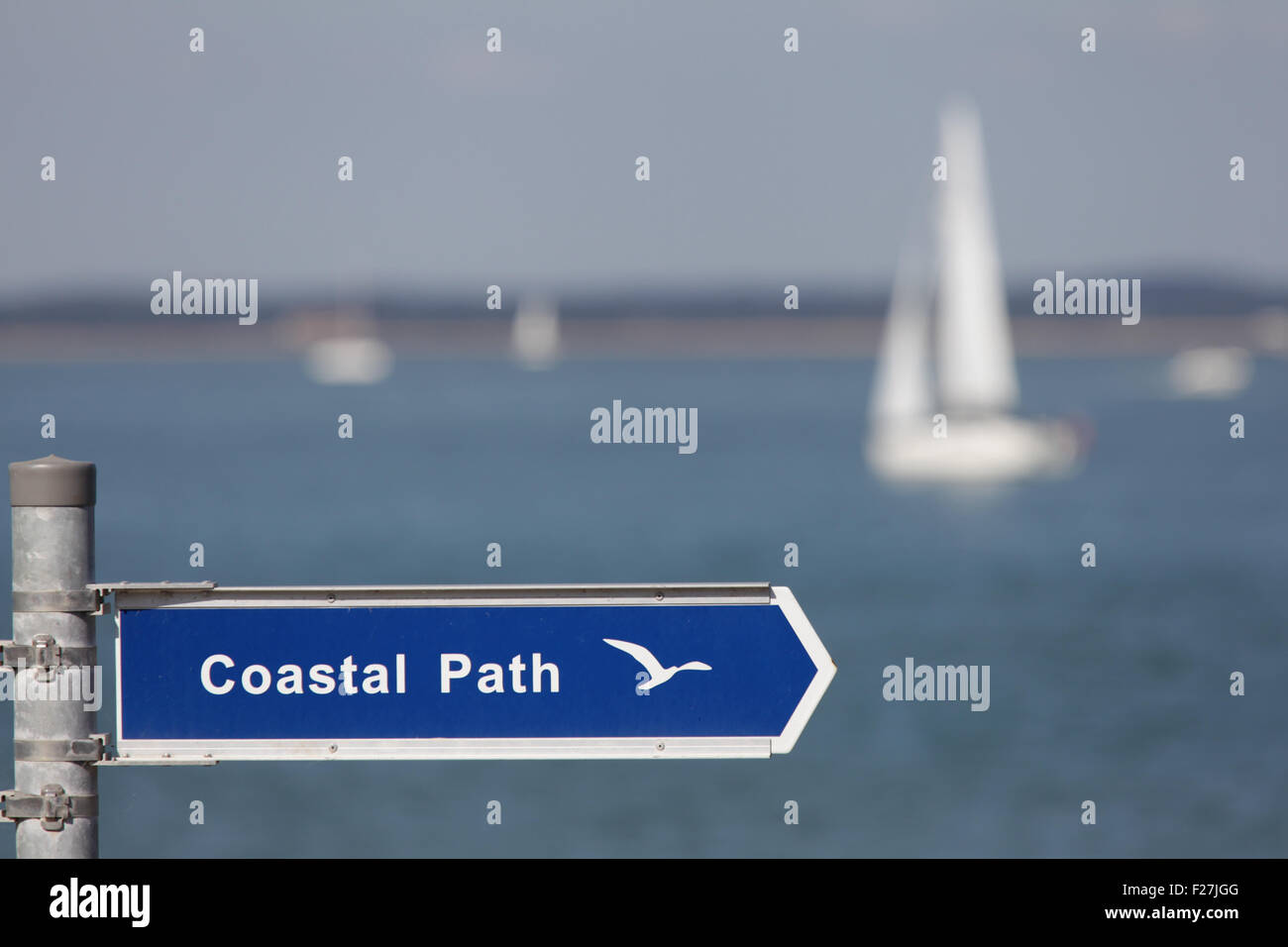 A coastal path sign with a sailing yacht in the background Stock Photo